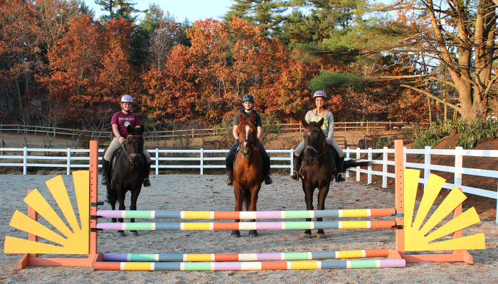 Three riders posing at a jump